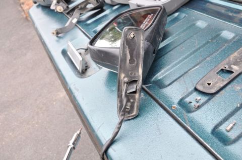 1996 Ford Bronco - Disassembled side mirror assembly and trim pieces laid out on a truck bed.
