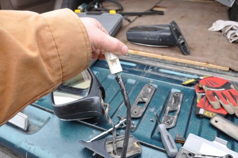 1996 Ford Bronco - Disassembled side mirror components and tools are laid out on a teal surface.