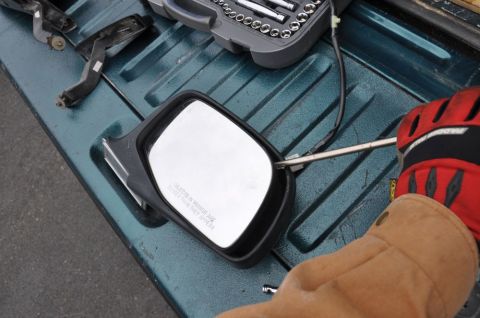 1996 Ford Bronco - A side mirror is being worked on, with a toolbox and other parts laid out on a textured surface.