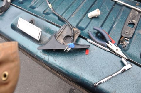 1996 Ford Bronco - Tools and a car mirror housing are laid out on the bed of a teal truck.