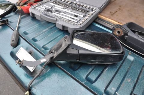 1996 Ford Bronco - Car side mirror, socket set, and screwdriver are laid out on a teal truck bed.