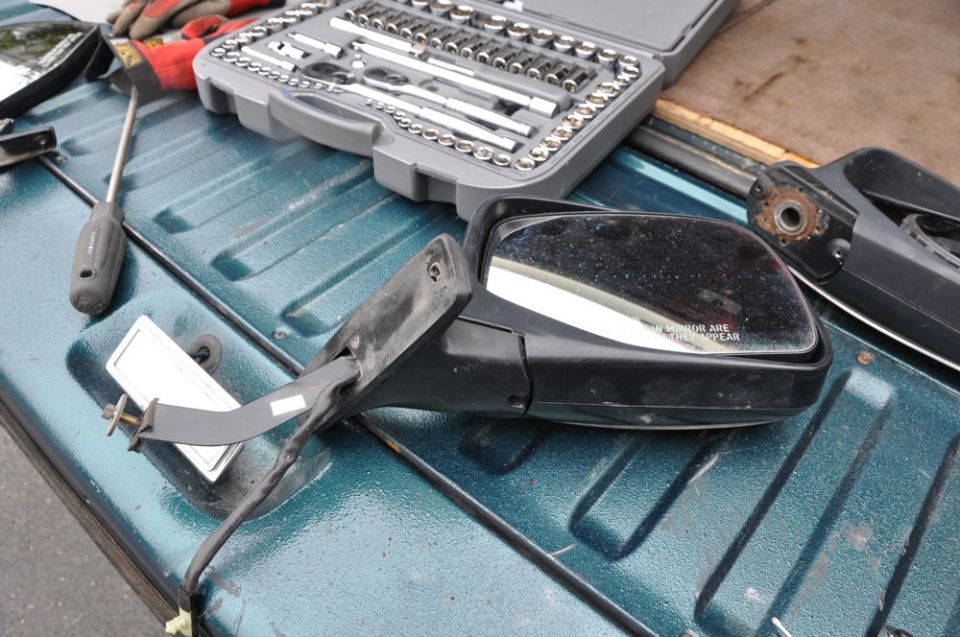 Car side mirror, socket set, and screwdriver on a teal truck bed