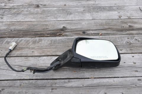1996 Ford Bronco - A detached side mirror with a visible wiring harness rests on a weathered wooden surface.