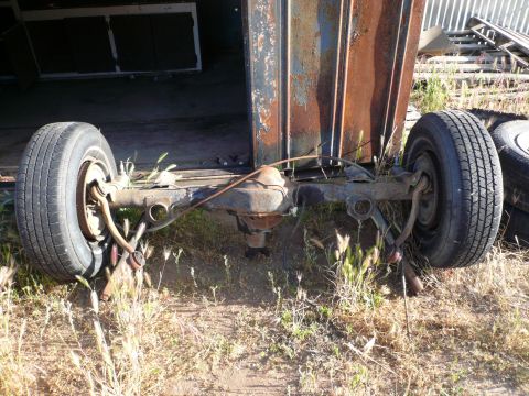 1975 Ford Ranchero - The rear axle and wheels of a vehicle are visible, showing signs of rust and disuse.