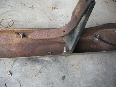 1966 Ford F-100 - Close-up view of a rusty bumper bracket assembly, likely from a truck, mounted on a concrete surface.