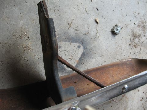 1966 Ford F-100 - A close-up view of a rusty metal truck bumper bracket and a section of chrome trim.