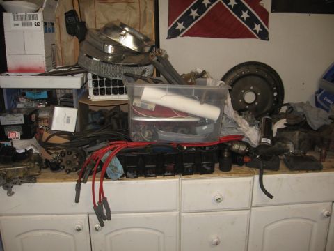 1966 Ford F-100 - Various automotive parts are laid out on a workbench, including a carburetor, distributor cap, and spark plug wires.