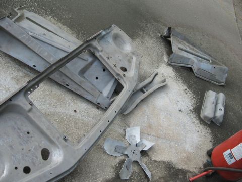 1966 Ford F-100 - Disassembled car body parts and a fan blade are laid out on a concrete surface with sandblasting equipment.