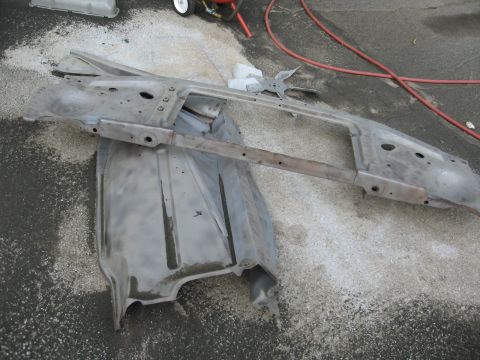 1966 Ford F-100 - Bare metal car parts, likely from the front end, are laid out on the ground, possibly for restoration.