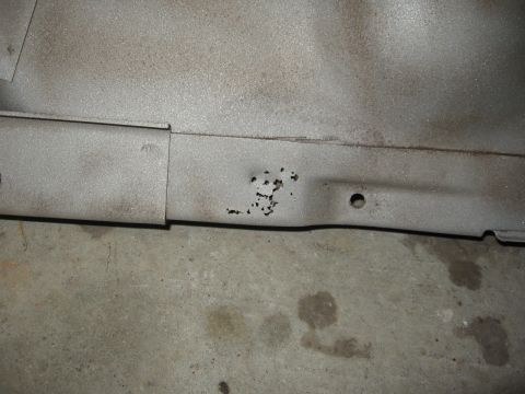 1966 Ford F-100 - Close-up of a corroded metal panel, likely a vehicle part, on a concrete floor.