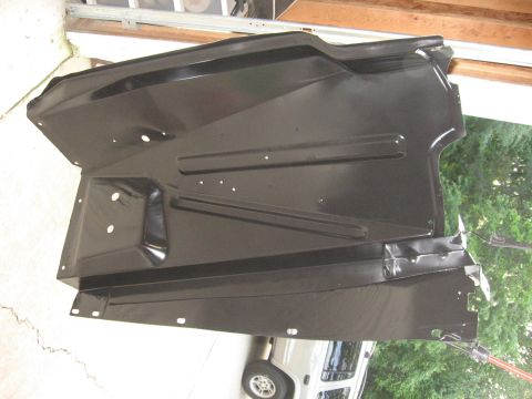 1966 Ford F-100 - This black metal panel, likely a fender liner or splash shield, features stamped ribs for rigidity and numerous mounting holes.