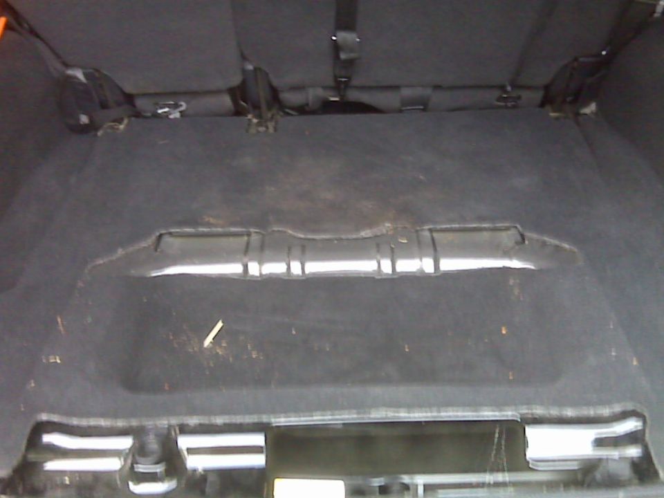 Cargo area floor with seats folded down, showing the carpeted surface and some debris