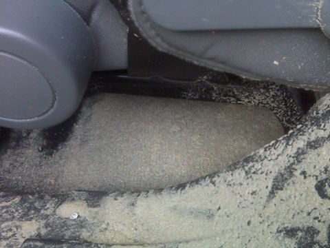 2008 Jeep Wrangler - The interior floor of a vehicle is covered in sand and debris, obscuring details of the vehicle's model year.