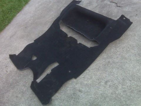 2008 Jeep Wrangler - This black carpet piece, likely an interior component, is shown laid out on a concrete surface.