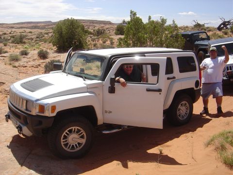 1986 Ford Bronco II - Two people pose with a white Hummer H3 in a desert off-road setting, with other vehicles visible in the background.