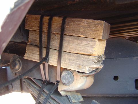 1986 Ford Bronco II - Wooden blocks are zip-tied to the vehicle's frame, likely for temporary support or modification.