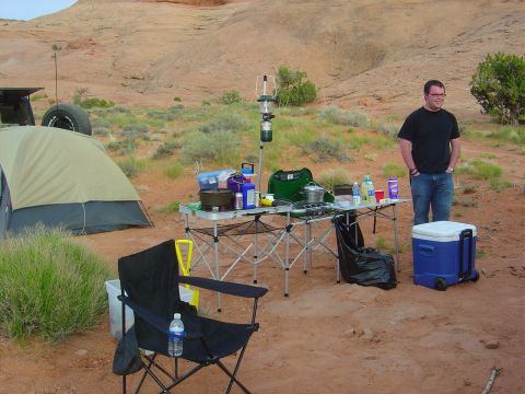 1986 Ford Bronco II - A campsite is set up in a desert landscape with camping equipment and a person standing nearby.