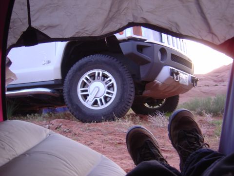 1986 Ford Bronco II - View of a white Hummer H3 from inside a tent, parked in a desert setting with rocky terrain.