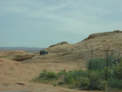1986 Ford Bronco II - An off-road vehicle navigates a challenging rocky terrain in a desert environment.