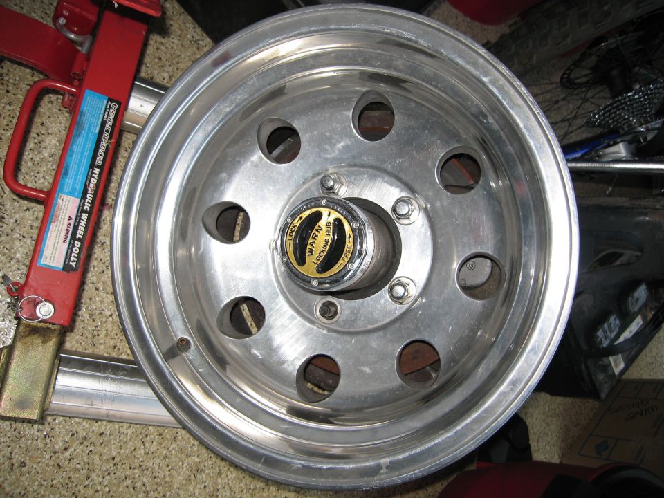 Warn locking hub on a polished aluminum wheel, with a hydraulic wheel dolly in the background