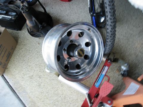 1986 Ford Bronco - A single polished alloy wheel is shown, likely for a truck or SUV, with a bicycle tire visible in the background.