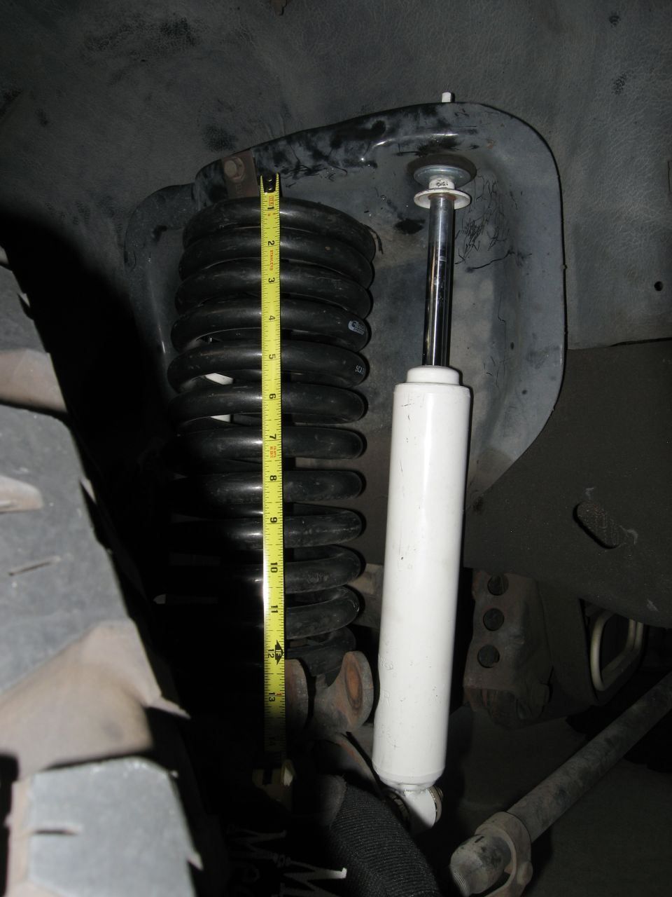 Suspension coil and white shock absorber measured with a yellow tape measure