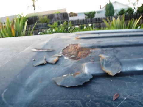 1986 Ford Bronco - The roof of a vehicle shows extensive rust and deterioration, with pieces of metal flaking off.