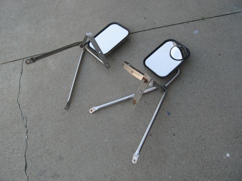 1986 Ford Bronco - Two side mirrors with chrome mounting hardware are shown resting on a concrete surface.