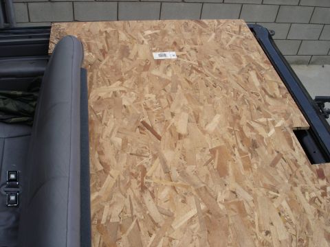 1995 Ford Bronco - A piece of plywood is placed over the cargo area of the vehicle, obscuring the view of the trunk space.