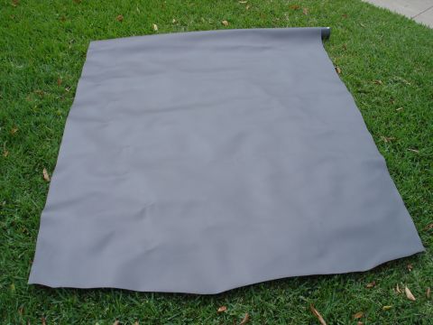1995 Ford Bronco - Gray tonneau cover, likely for a truck bed, rolled up on a grassy surface.