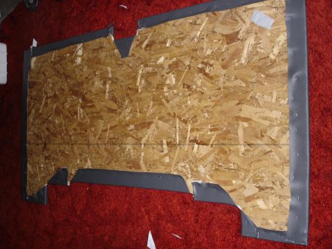 1995 Ford Bronco - Custom car interior panel constructed from OSB and trimmed with gray material, placed on a red carpeted surface.