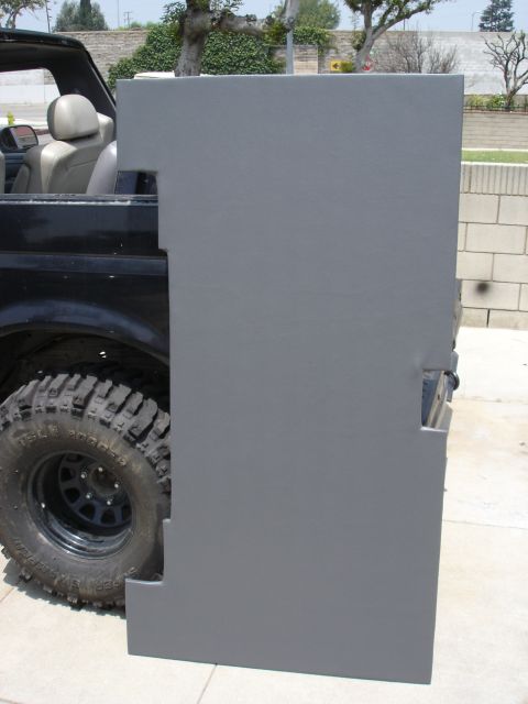 1995 Ford Bronco - A large gray textured-coated fabricated panel, likely a removable hardtop or body panel, leans against a topless lifted Ford Bronco fitted…