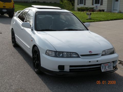 1994 Acura Integra - White 1994 Acura Integra coupe with black wheels and sunroof, parked on street with yellow SUV in background.