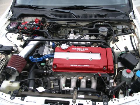 1994 Acura Integra - Close-up of a modified Honda engine bay a red valve cover and chrome intake piping.