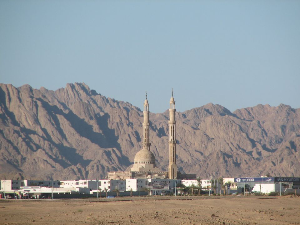 Mosque with twin minarets in front of barren desert mountains