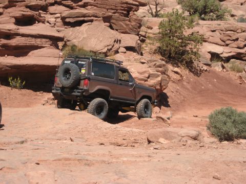 1986 Ford Bronco II - This 1986 Ford Bronco II tackles a challenging off-road course amidst red rock formations.