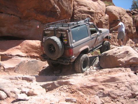 1986 Ford Bronco II - A Ford Bronco II navigates a challenging rocky trail with a driver guiding it.