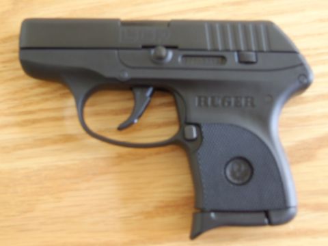 2002 Jeep TJ - A black Ruger LCP pistol is shown on a wooden surface, with visible branding and a website logo.