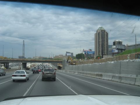 1995 Ford C-350 (Centurion Conversions) - A view from a vehicle driving on a highway with ongoing construction and city buildings in the background.