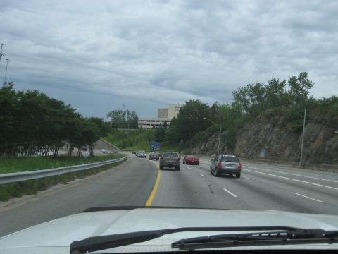 1995 Ford C-350 (Centurion Conversions) - Traffic moves along a highway with a building and rocky terrain visible.