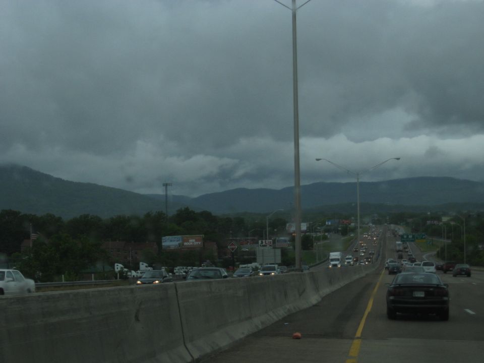 Highway traffic under a cloudy sky with mountains in the background