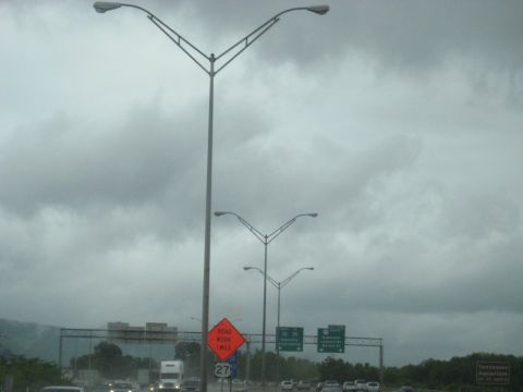 1995 Ford C-350 (Centurion Conversions) - A cloudy day on the highway with multiple lanes of traffic and overhead streetlights.