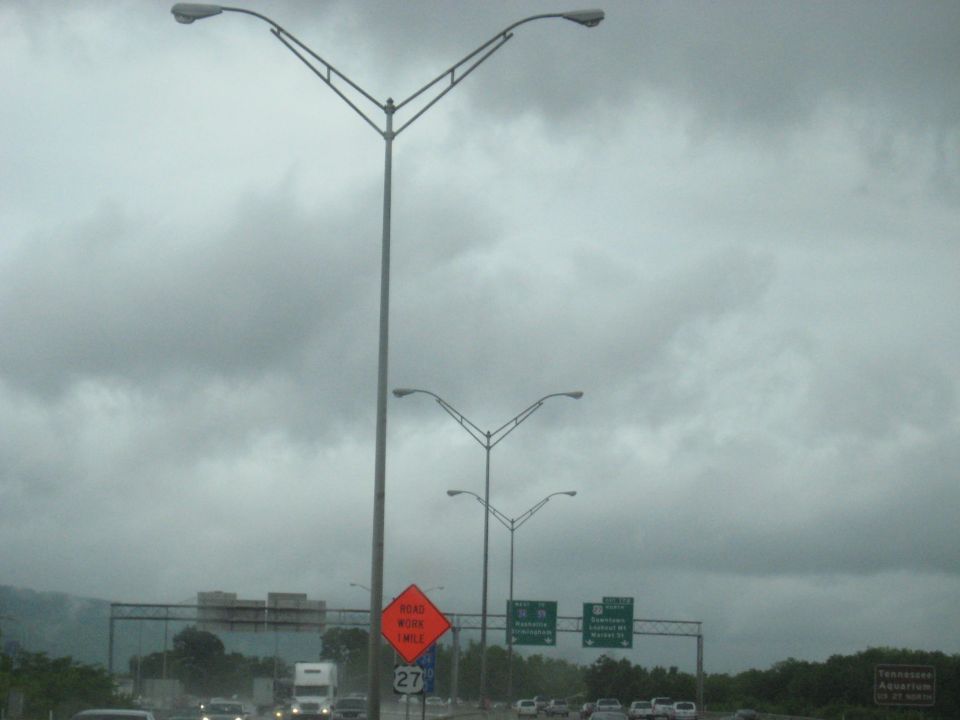 Highway with streetlights, traffic, and a road work sign