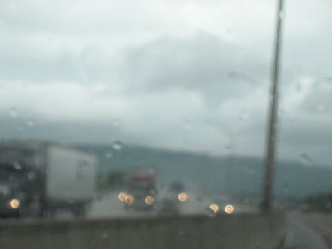 1995 Ford C-350 (Centurion Conversions) - Multiple trucks drive on a highway during a rainstorm, with visibility reduced by water droplets on the glass.