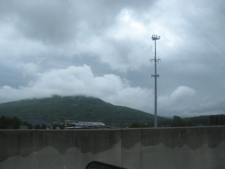 Cell tower and mountain under cloudy sky