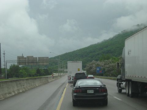 1995 Ford C-350 (Centurion Conversions) - Traffic moves along a highway under a cloudy sky with a green mountain visible.