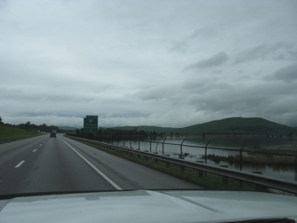 Highway scene with a green sign and a body of water on the right