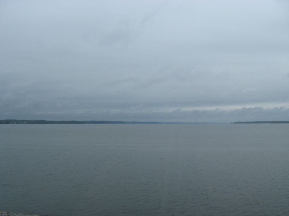 Overcast sky above a wide body of water with distant shorelines