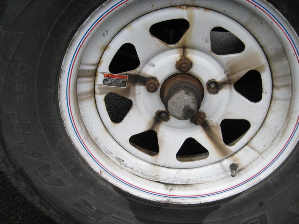 Close-up of a white trailer wheel with a red and blue stripe, showing a tire with 'REVO' visible