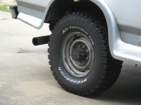 1995 Ford C-350 (Centurion Conversions) - Close-up of a vehicle's rear tire and exhaust pipe, showing off-road tire tread.